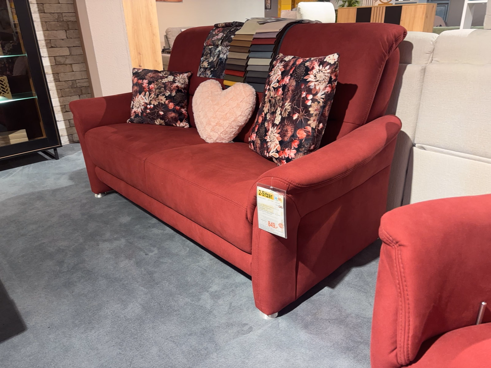 Frontansicht des Sofas aus etwas größerer Distanz; rechts im Bild ist ein weiterer Sessel/Sofa-Teil in gleichem Bezug